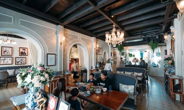 ภายในร้านอาหารตกแต่งสไตล์คลาสสิก ผนังสีขาว โคมไฟระย้า และลูกค้านั่งรับประทานอาหาร